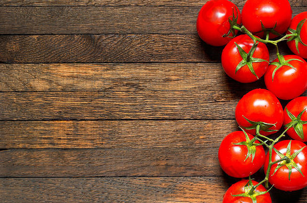 木制背景的俯视图，右侧为红色西红柿，左侧为空间。闭合。蔬菜上的水滴。健康营养观