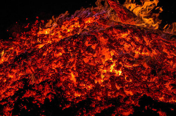 点火。温暖寒冷的冬夜。木柴和炽热的煤炭的宏观照片。燃烧树枝和木头。壁炉里的火焰