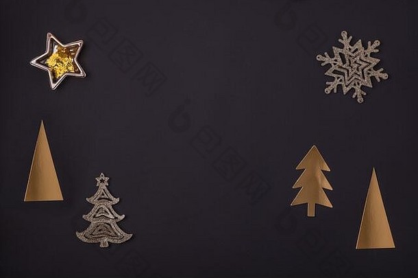 新年和圣诞节贺卡由金色的圣诞装饰品制成——黑色纸背景上的圣诞树、星星和雪花。俯视图、平面布局、空间