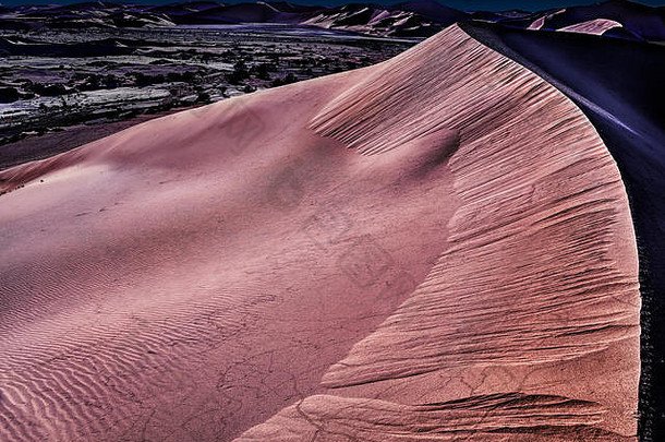 夜晚的纳米布沙漠，有橙色的沙丘和星空。