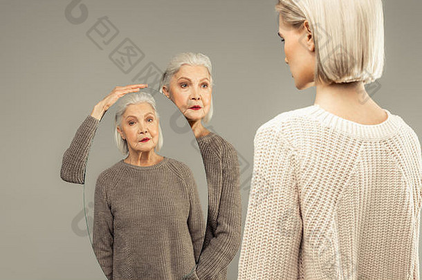 不错的岁的女人持有椭圆形镜子