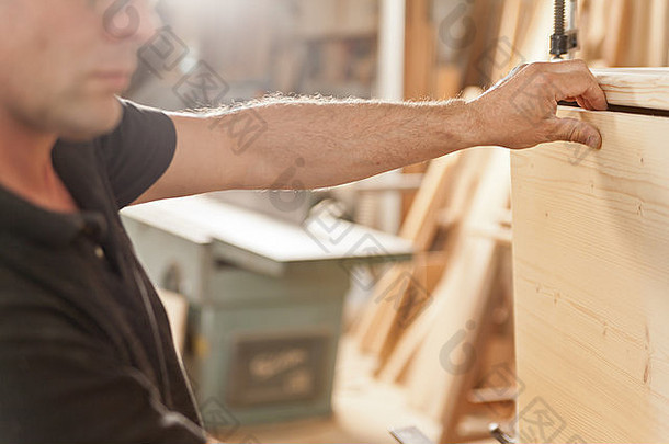 木匠的手臂和手小心地将部件放置在一件手工制作的家具中