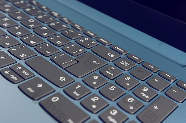 Gradient Blue全新笔记本电脑，带黑色键盘特写，位于蓝色木质表面工作室拍摄