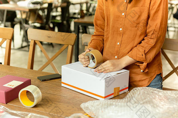 创业小企业的女老板在工作场所打包纸箱。