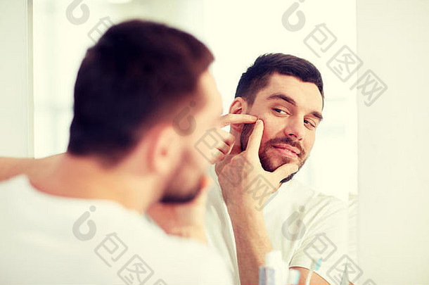 男子在浴室镜子前挤痘痘