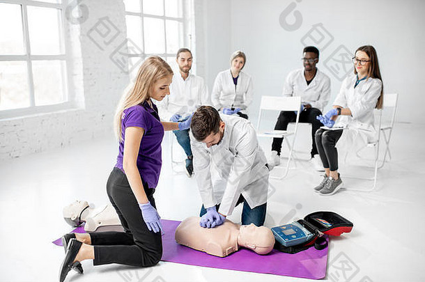 一群年轻的医生在白色房间的急救训练中练习用医用假人进行人工呼吸