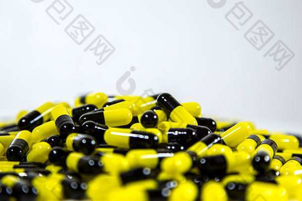 许多黑色和黄色的药丸和药片的特写镜头被隔离在白色背景上。处方药。<strong>药物</strong>、止痛药和<strong>药物滥用</strong>