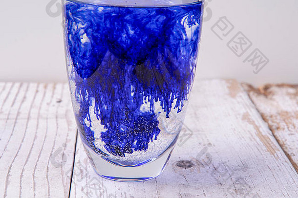 蓝色液体在装满水的玻璃杯中扩散