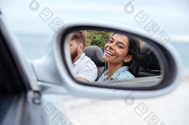 美丽的微笑着的女人在<strong>汽</strong>车后视镜里看着自己的倒影