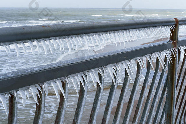 篱笆上有冰，金属结构上有冰柱