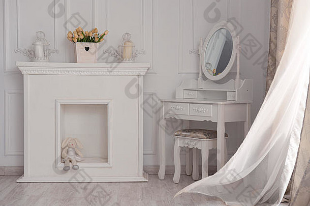漂亮的白色房间，带壁炉和带镜子的桌子。