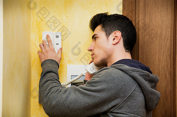 青少年或年轻人在公寓里接听对讲机，按下按钮打开大门