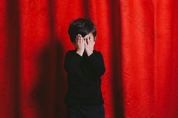 一个三岁男孩的工作室肖像，手放在脸上