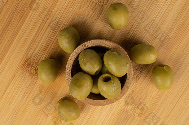 整批腌制青橄榄放在竹碗里，平铺在轻质木材上