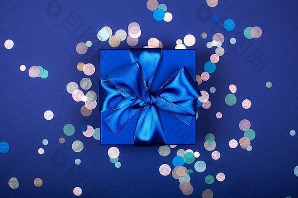 带蝴蝶结的蓝色礼品盒，采用单色、时尚、平铺的五彩纸屑构成