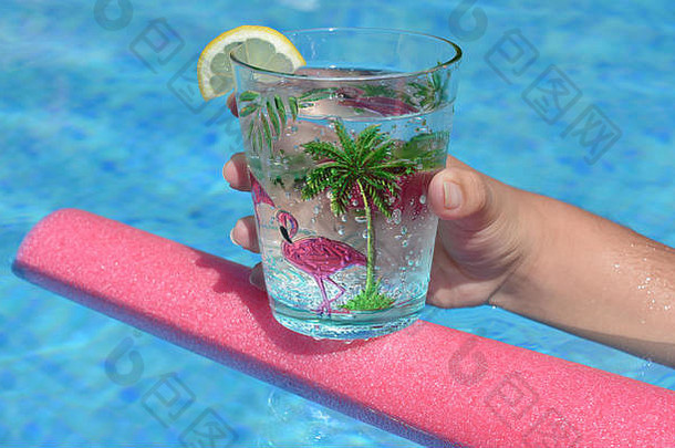 在游泳池里，一个年轻女子手里拿着一杯饮料，漂浮在游泳池的面条上。夏日氛围，保持凉爽，享受乐趣。