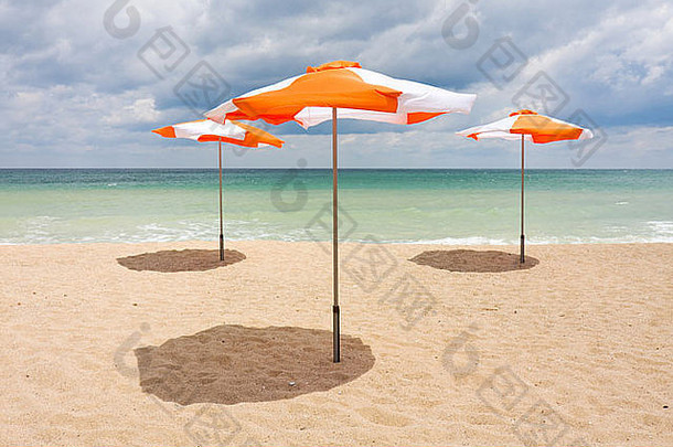 白色沙滩上的沙滩伞，多云的蓝天和阳光