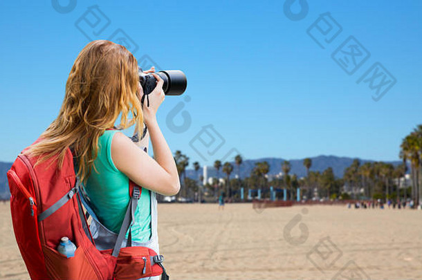 威尼斯海滩上背着背包和照相机的女人