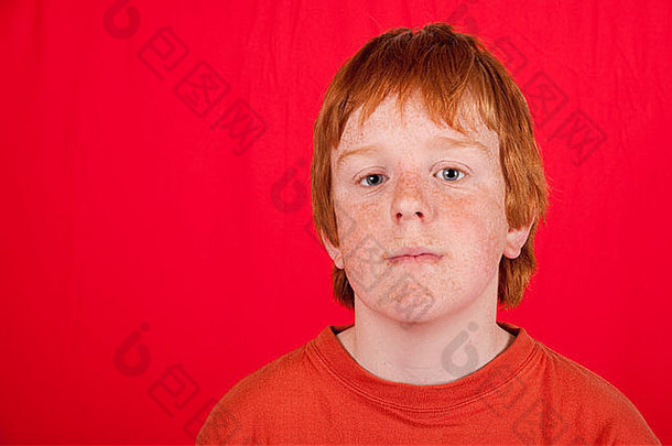 红头发的十几岁男孩，在红色背景下表情忧郁