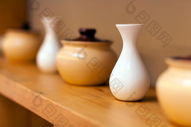米色陶瓷壶和白色小<strong>花瓶</strong>，用于木架上的颜色，特写