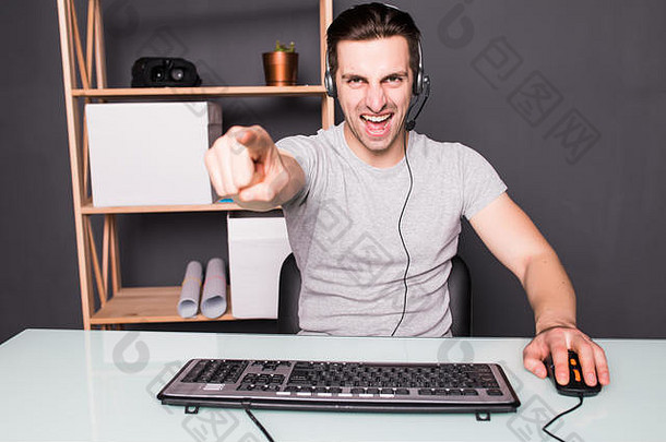 年轻人或黑客戴着耳机和眼镜，用pc电脑玩游戏，手指指着你们