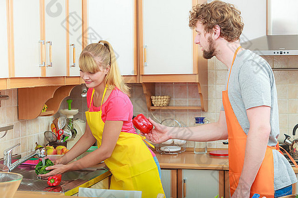 年轻夫妇一起做饭，在厨房的水流下清洗新鲜蔬菜红辣椒绿莴苣，准备沙拉素食