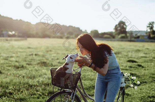 在温暖的阳光下，女孩骑着自行车和小狗在田野里散步