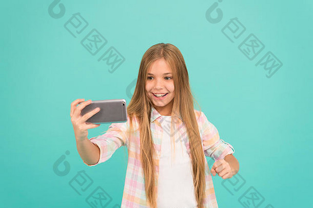 视频通话概念。女孩拿着智能手机自拍。社交网络自拍。在线流媒体或拍摄视频日志。你好，世界，这是我的频道。让我拍自拍。小女孩拿着智能手机。
