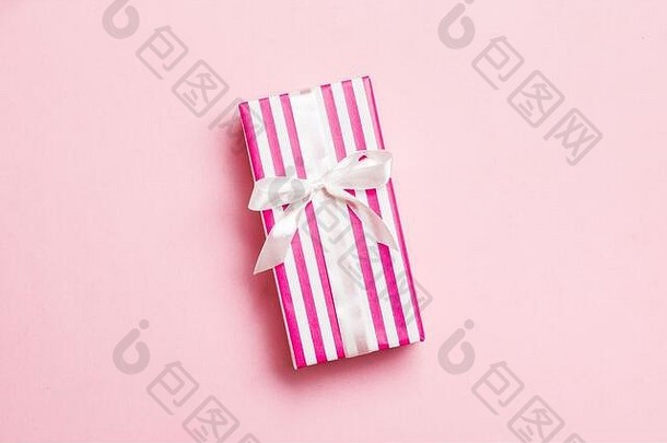 在纸上用粉红色<strong>背景</strong>上的白色丝带包装圣诞或其他节日手工礼品。礼品盒，彩<strong>台</strong>礼品装饰，t