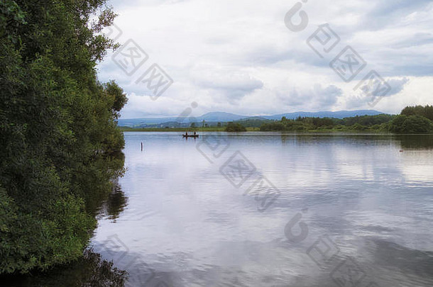 两名男子在苏格兰唯一的湖泊明泰湖平静的水域中乘船捕鱼的平静场景。