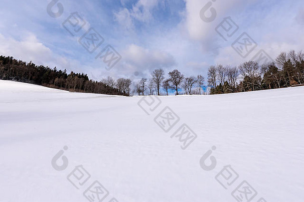 雪白的冬天田园诗般的农田山顶、田野、树木、晴朗的蓝天、上山的景色、云朵