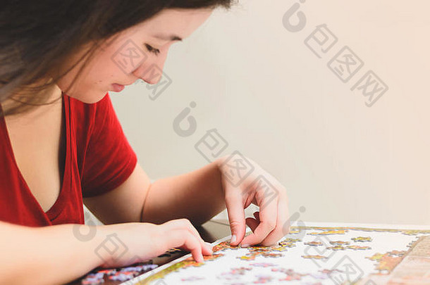 一名女子正在尝试匹配拼图游戏的碎片。玩游戏，侧视。