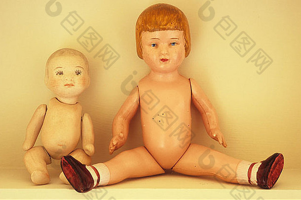 传统的bisque娃娃坐在架子上，旁边是腿张开的复古赛璐珞娃娃