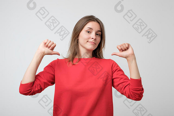 穿着红色毛衣的年轻漂亮女人骄傲而自信，指着手指，以身作则。自私和以自我为中心的人的概念