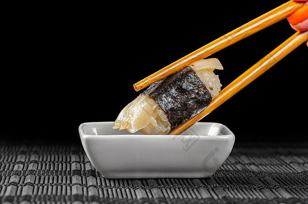 在黑色背景上蘸酱油的寿司