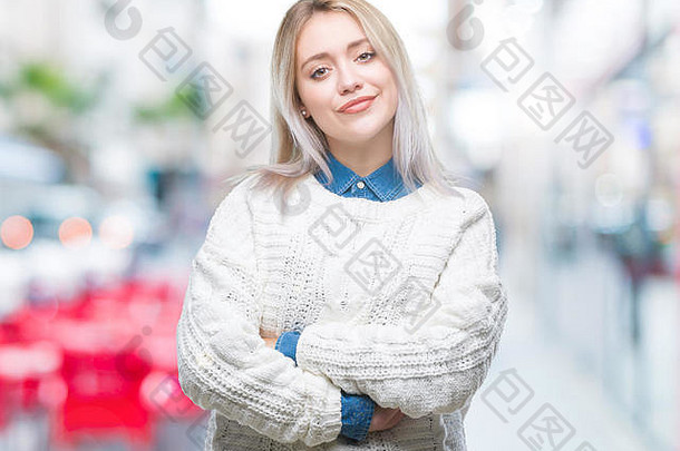 年轻的金发女郎，穿着冬衣，在孤立的背景下微笑着，双臂交叉看着摄像机。积极的人。