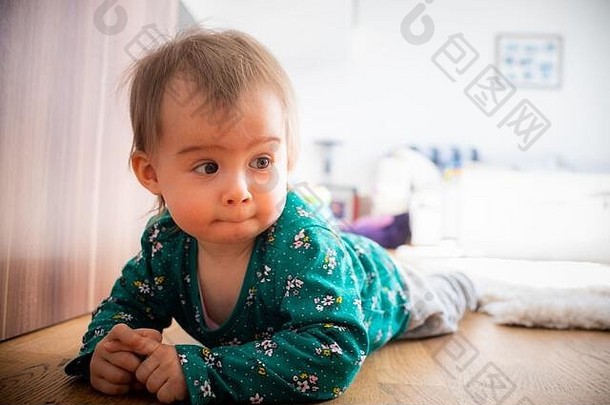 12-15个月大的可爱白人女孩双手合十躺在木地板上