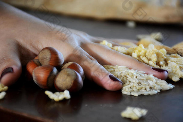 用女人的手放在桌子上的谷物、坚果和谷类食品