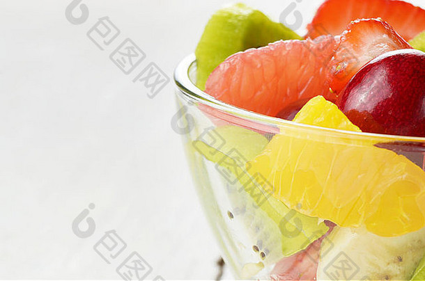 白色桌子上的玻璃碗和混合水果沙拉