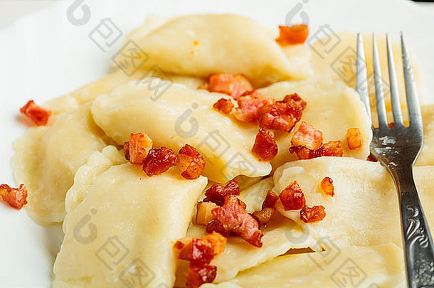 以叉子为食物背景，在饺子上撒上猪肉抓痕的特写镜头。传统波兰菜。