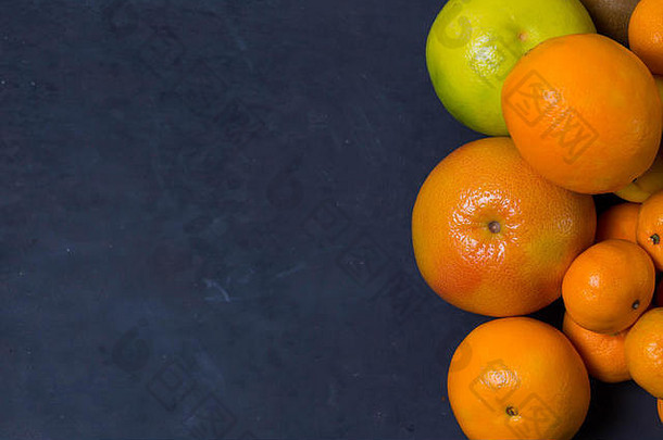 许多美丽明亮的柑橘、柑橘、葡萄柚甜点位于图像右侧，边缘为深蓝色的不均匀区域