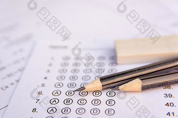 答案纸上的铅笔和橡皮擦或标准化考试表格上的答案冒着气泡。<strong>选择题</strong>答卷