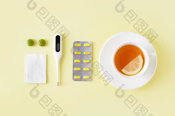药片、温度计和一杯黄色背景的茶。感冒和流感治疗套装。平面布置，俯视图。免费拷贝空间。