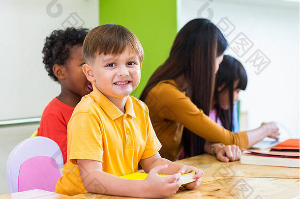 白人男孩种族孩子微笑着在教室里与朋友和老师在幼儿园学习，教育理念