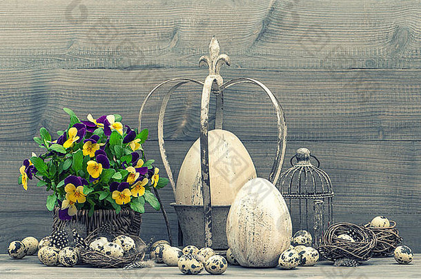 复活节装饰有彩蛋、三色堇花、鸟巢和鸟笼。复古风格色调图片