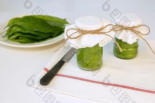 新鲜的野蒜香蒜酱放在厨房桌子上用熊韭菜香草制成的罐子里。健康的超级食品成分。