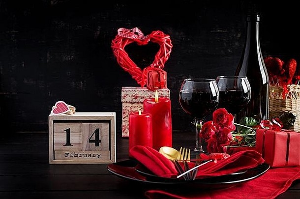 情人节一天晚餐表格设置礼物红色的玫瑰心葡萄酒杯黑暗背景