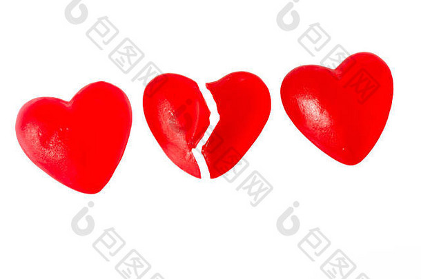 破碎的心或心痛的概念，三个鲜红色果冻心形糖果相邻，中间一个切成两半，在白色背景上隔离