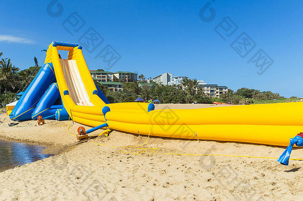 在暑假期间，海滩海洋公共娱乐设施沿着高水滑梯充气结构向下行驶。