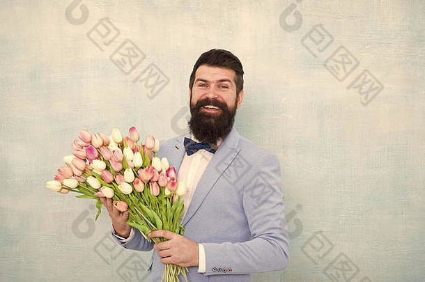 生日祝福。送给女朋友最好的花。给她鲜花。男人胡子西装蝴蝶结举行郁金香花束。给她带来浪漫惊喜的绅士。送花。绅士浪漫约会。